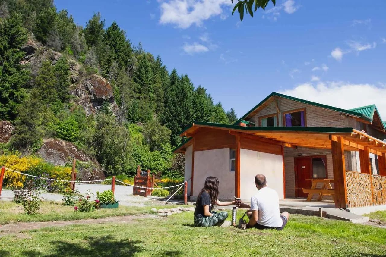 Fachada del Hostel Huellas en Lago Puelo, Patagonia, rodeado de vegetación de montaña