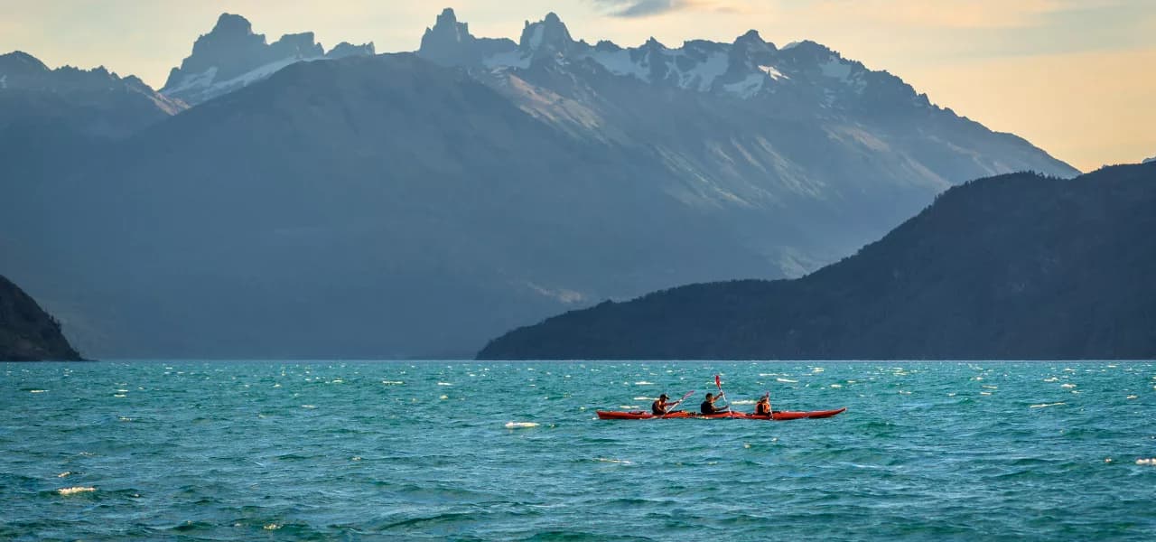 Kayak sobre las aguas turquesas de Lago Puelo, rodeado de montañas de la Comarca Andina